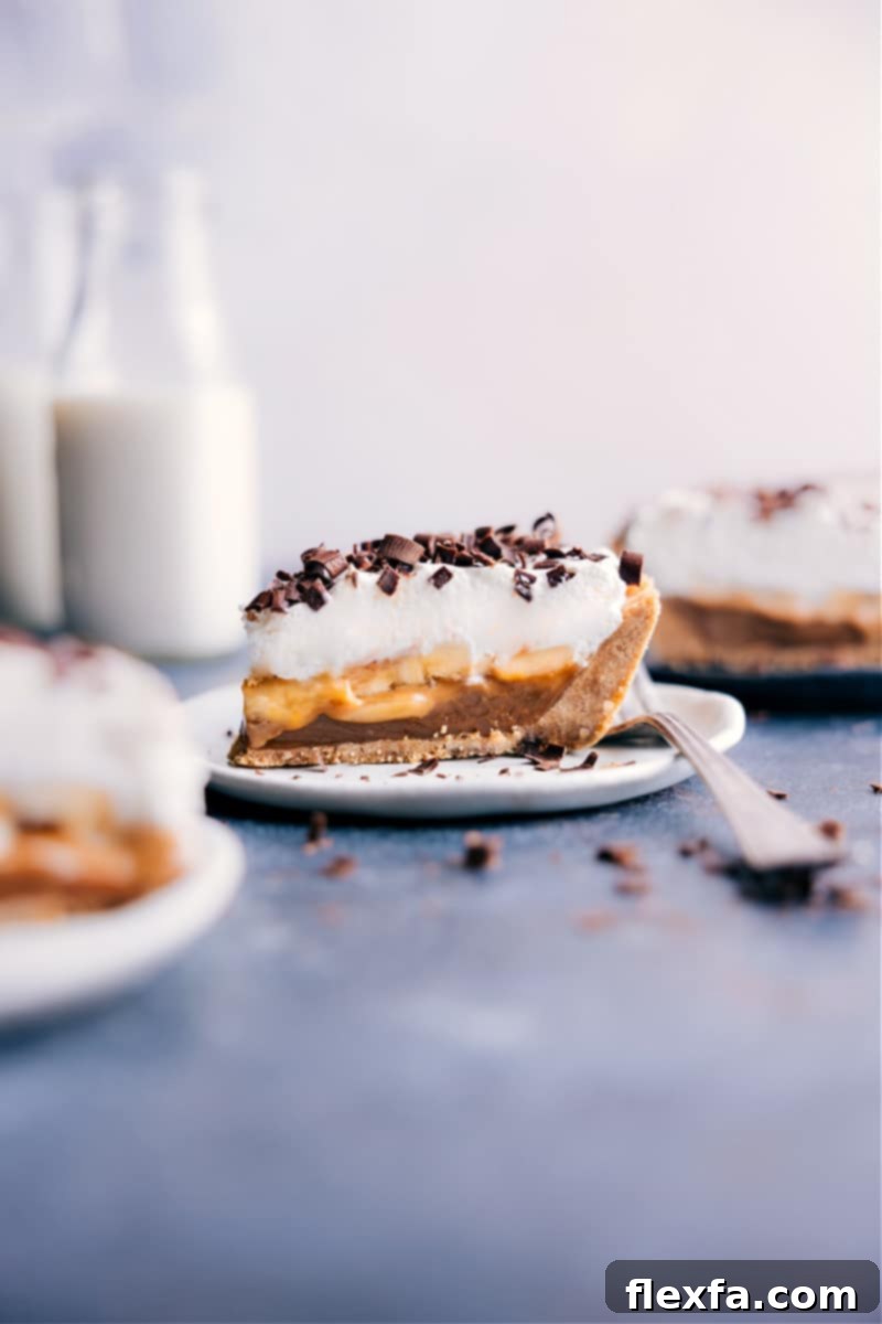 A delectable slice of Banoffee Pie on a white plate, showcasing its layers of golden crust, rich caramel, fresh bananas, and a swirl of whipped cream topped with chocolate shavings.