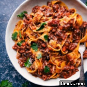Slow-Cooked Ragu Perfection 7 A bowl of rich Ragu sauce with ground beef and Italian sausage, served with pappardelle pasta and garnished with fresh herbs.