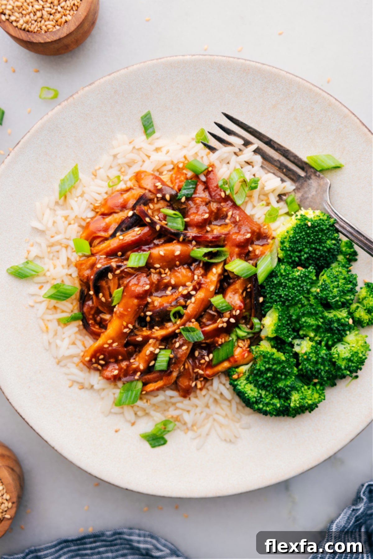 Honey Garlic Chicken Thighs served on a bed of fluffy rice, garnished with fresh green onions and accompanied by steamed broccoli on the side.