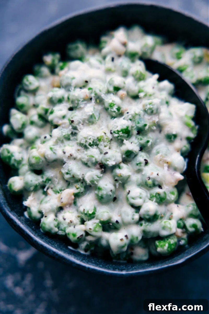 Up-close overhead image of a bowl of Creamed Peas ready to be enjoyed, garnished with a sprig of fresh parsley.