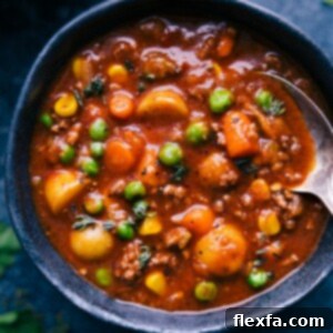 Close-up of a serving of Vegetable Beef Soup in a white bowl, garnished with parsley.
