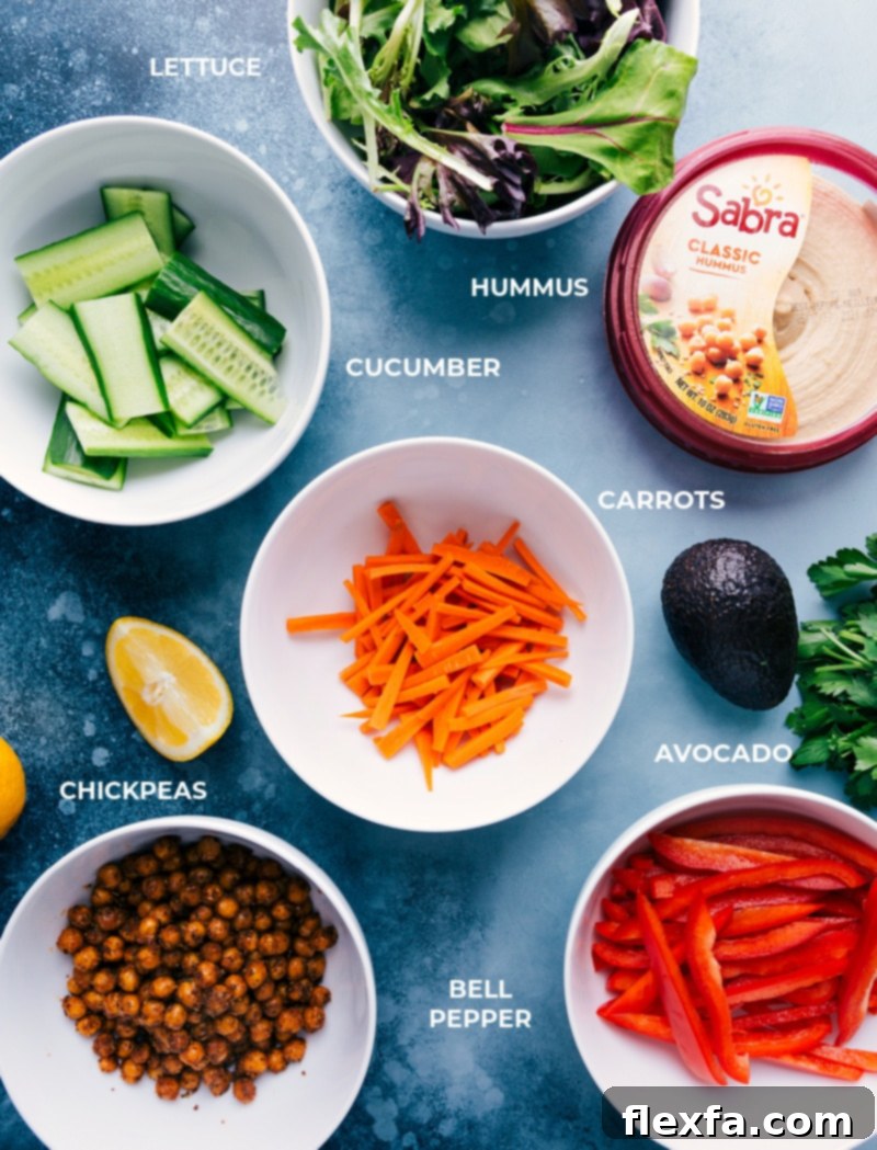 Ingredient shot: All fresh, healthy components including chickpeas, hummus, and crisp vegetables, ready for easy 30-minute Hummus Wraps. Perfect for a quick, wholesome lunch. Recipe via ChelseasMessyApron #healthy #dinner #lunch #quick #easy #simple #best #clean #cleaneating #wholefoods #chickpeas #vegetarian #vegan #hummus #wrap A vibrant selection of ingredients laid out, featuring fresh vegetables, a can of chickpeas, a bowl of hummus, and tortillas, essential for making delicious hummus wraps.