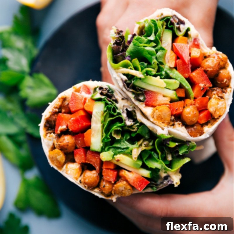 Finished Hummus Wraps: Perfectly rolled and generously filled with crispy chickpeas, fresh vegetables, and creamy hummus for a satisfying meal. Recipe via ChelseasMessyApron #healthy #dinner #lunch #quick #easy #simple #best #clean #cleaneating #wholefoods #chickpeas #vegetarian #vegan #hummus #wrap Close-up overhead shot of two perfectly rolled Hummus Wraps, showing the vibrant fillings.