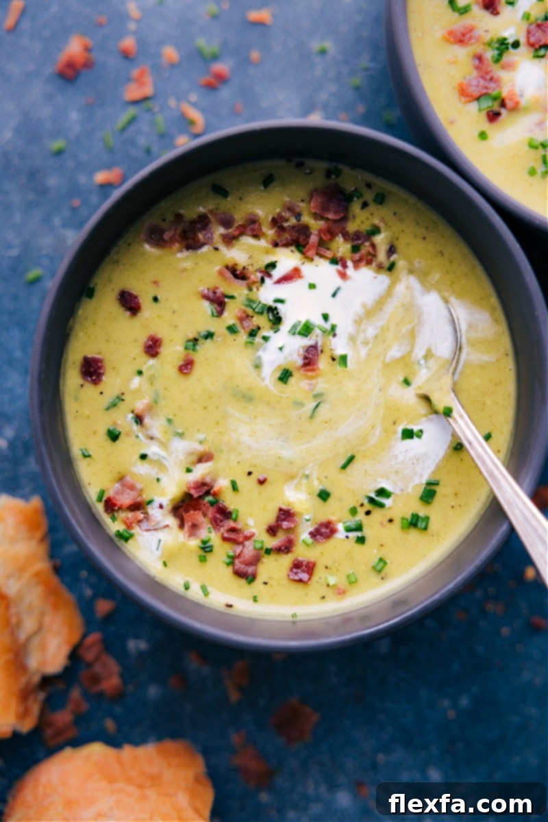 An inviting overhead shot of a cozy table setting featuring a bowl of creamy broccoli soup, a slice of crusty bread, and a warm, comforting ambiance.