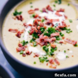 A delicious bowl of creamy, cheesy broccoli soup with fresh garnishes.