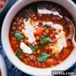 A bowl of hot Beef Lentil Soup, garnished with fresh parsley and a dollop of yogurt.