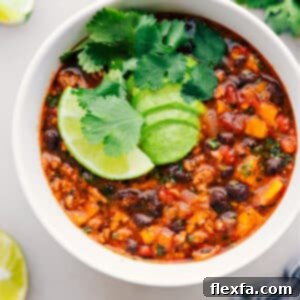 A beautifully presented bowl of Beef Enchilada Soup with fresh toppings.