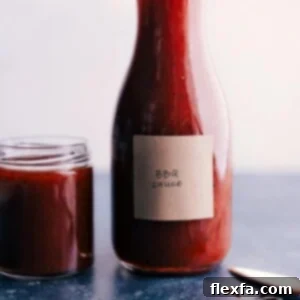 A small bowl of homemade BBQ sauce with a spoon, ready to be tasted or served.