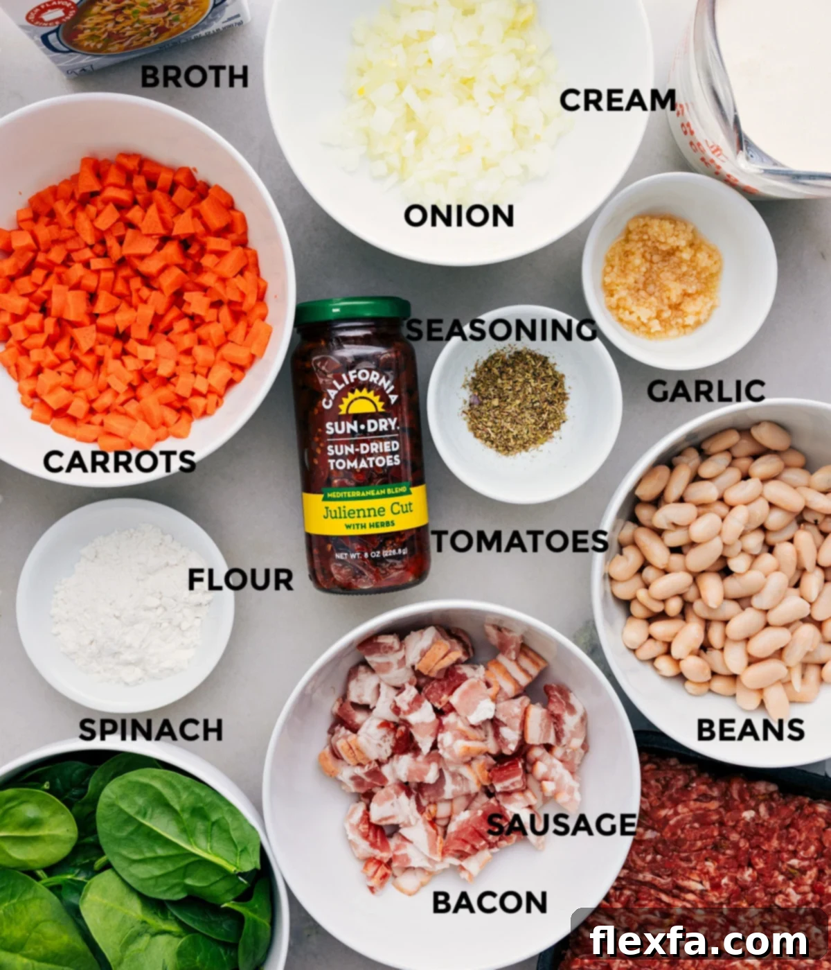 All the fresh ingredients laid out for making Tuscan Soup, including vegetables, seasoning, sun-dried tomatoes, white beans, Italian sausage, bacon, spinach, flour, chicken broth, and heavy cream.