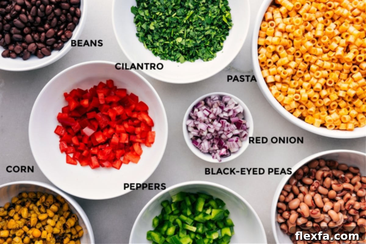 Ingredients In Cowboy Caviar Pasta Salad A selection of fresh, prepped ingredients for Cowboy Caviar Pasta Salad, including vibrant bell peppers, red onion, cilantro, black beans, black-eyed peas, and cooked ditalini pasta with corn.