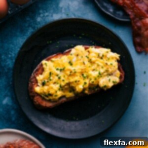 Close-up image of the finished creamy scrambled eggs on a plate, garnished with fresh herbs.