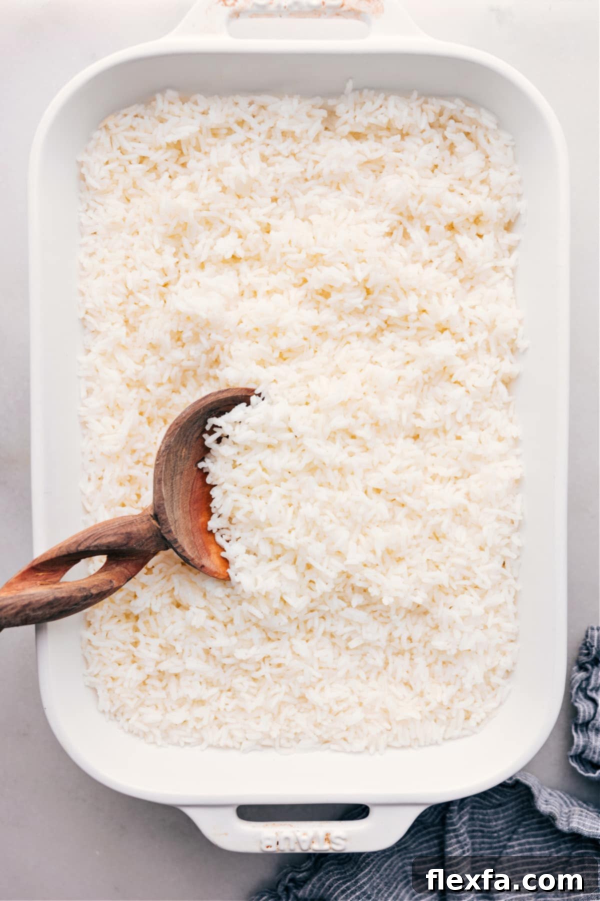 How To Make White Rice fresh out of the oven. A close-up of perfectly cooked, fluffy white rice in a baking dish, garnished with a sprig of fresh herb.