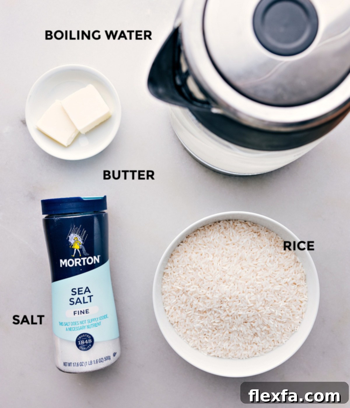All the ingredients used in this recipe set out for easy assembly. A baking dish with rice, salt, butter, and a kettle of boiling water ready to be combined.