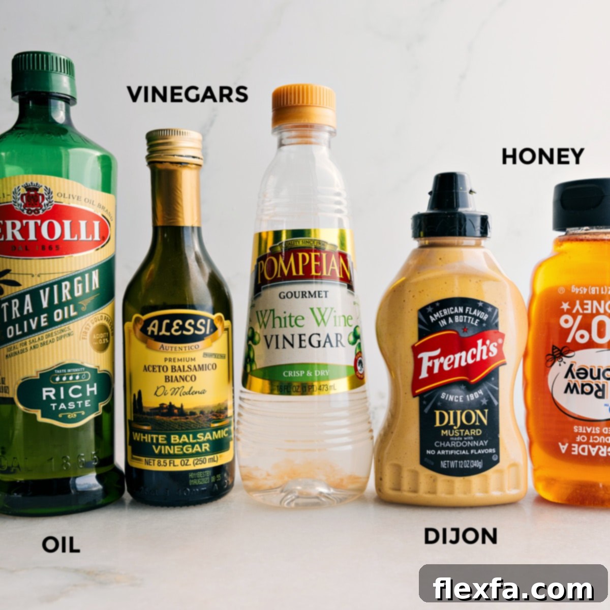 All the essential ingredients for making white balsamic vinaigrette laid out neatly: high-quality olive oil, white balsamic vinegar, white wine vinegar, creamy Dijon mustard, and golden honey.