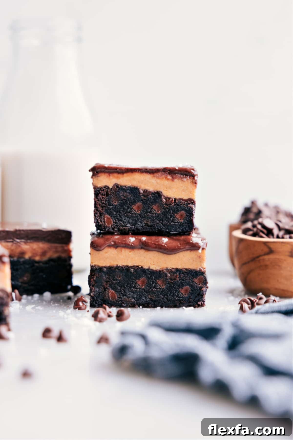 Stacked Buckeye Brownies show off their yummy layers: fudgy brownie, creamy peanut butter, and shiny chocolate topping.
