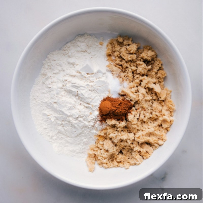 Process shot showing all-purpose flour, light brown sugar, and ground cinnamon added to a mixing bowl, ready to be combined for streusel.