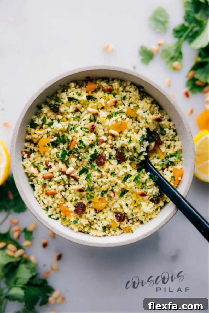 Delicious and easy couscous recipe with flavorful mix-ins. A beautifully prepared couscous recipe in a ceramic bowl, garnished with a vibrant array of fresh herbs, golden raisins, and toasted pine nuts, ready to be served. Ideal as a quick, easy, and family-friendly side dish for any meal.