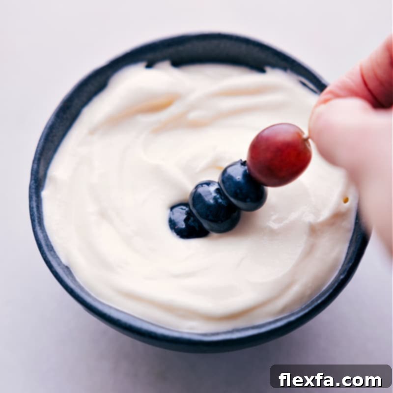 Image of a piece of fruit from the Rainbow Fruit Tray being dipped into the creamy dip.