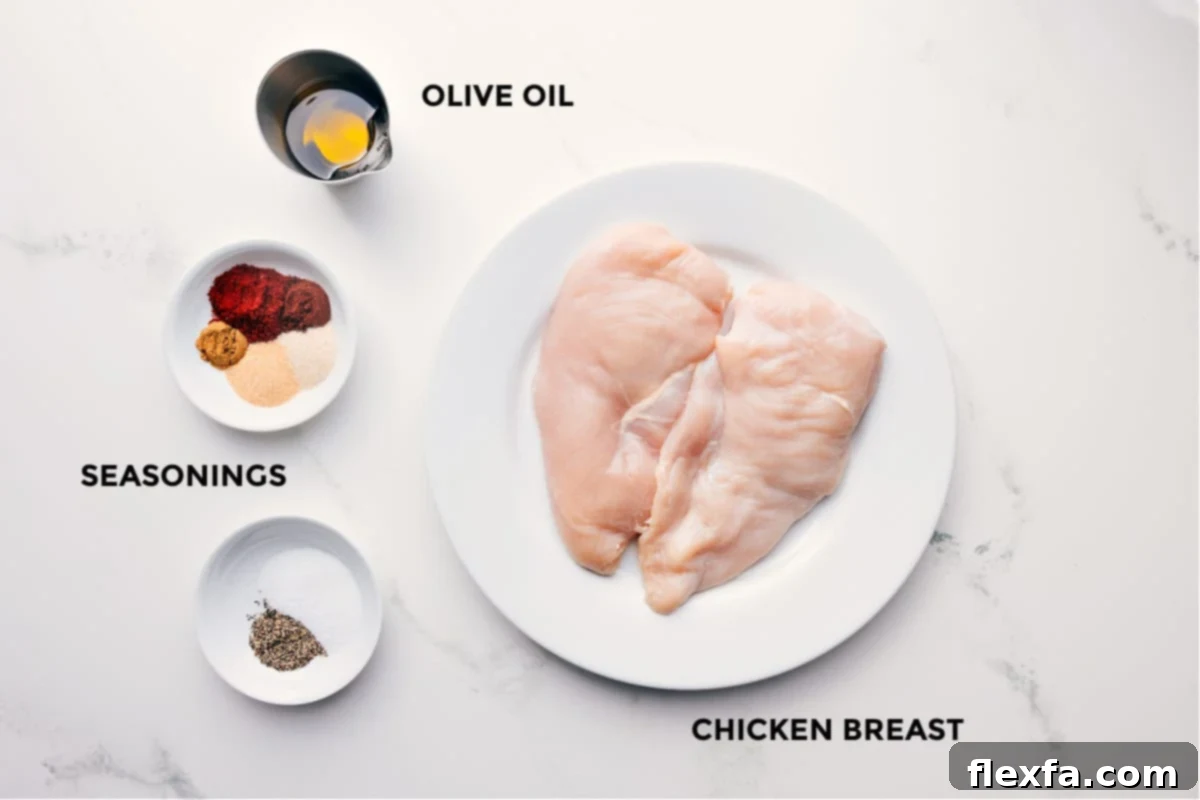 All the fresh ingredients for this baked chicken breast recipe, including olive oil, various seasonings, and raw chicken breasts, neatly arranged.