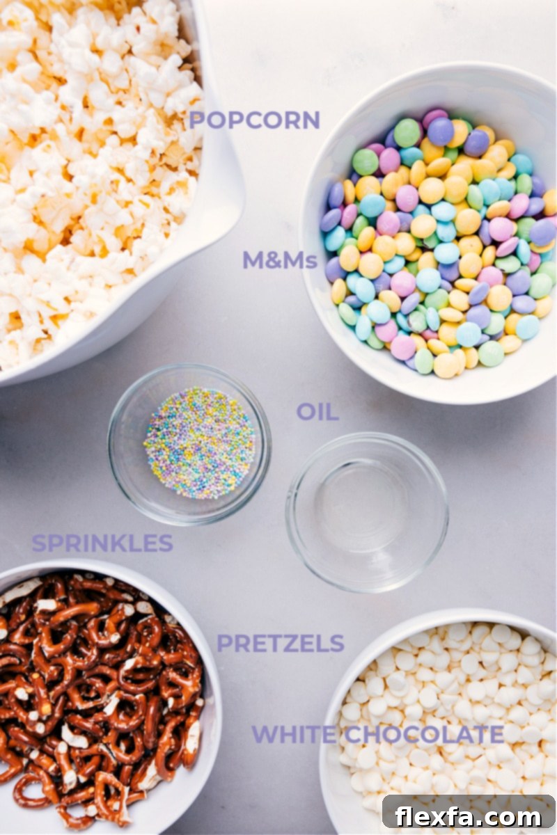 A bowl filled with all the ingredients for Easter Popcorn: popped popcorn, mini pretzels, pastel M&M's, white chocolate chips, and vegetable oil.