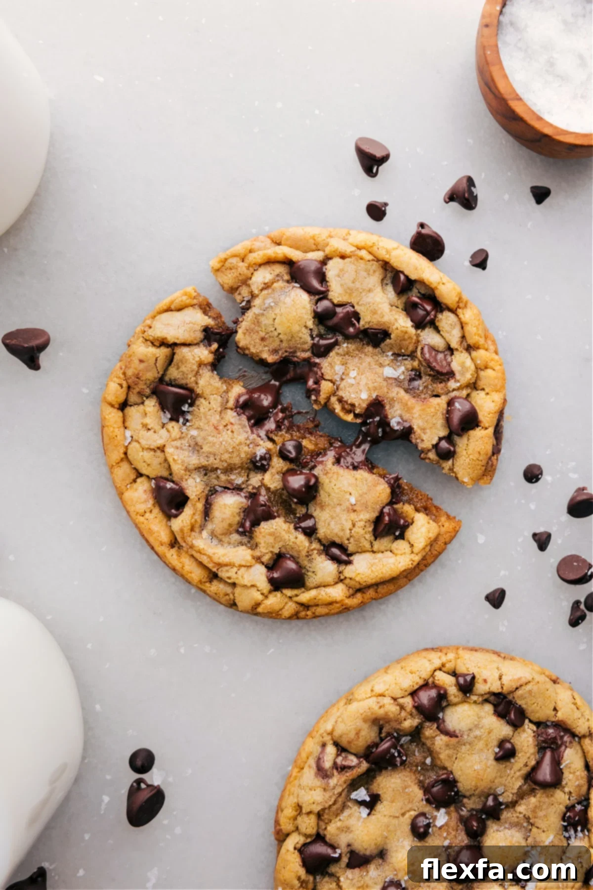 A freshly baked single-serve chocolate chip cookie, broken in half to reveal its warm, gooey, and utterly delicious chocolate-filled center.