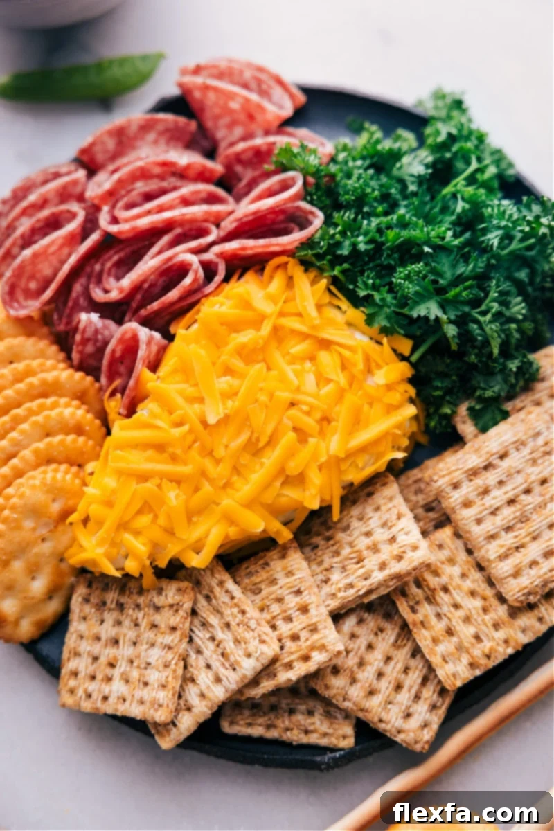Overhead image of the festive Carrot Cheeseball, garnished with vibrant curly parsley, presented beautifully on a wooden board with an assortment of crackers and fresh vegetables like celery, bell peppers, and cherry tomatoes