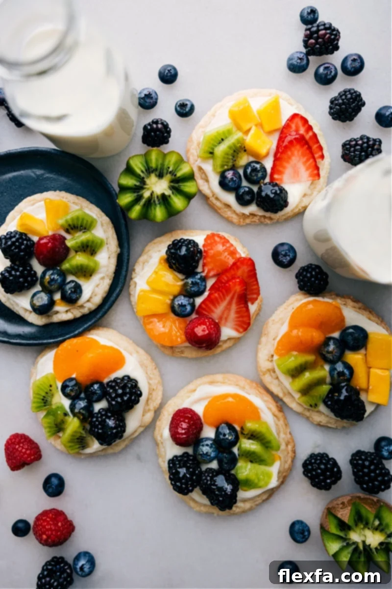 Overhead image of beautifully arranged sugar cookie fruit pizzas featuring colorful fresh fruit toppings and a shiny glaze.