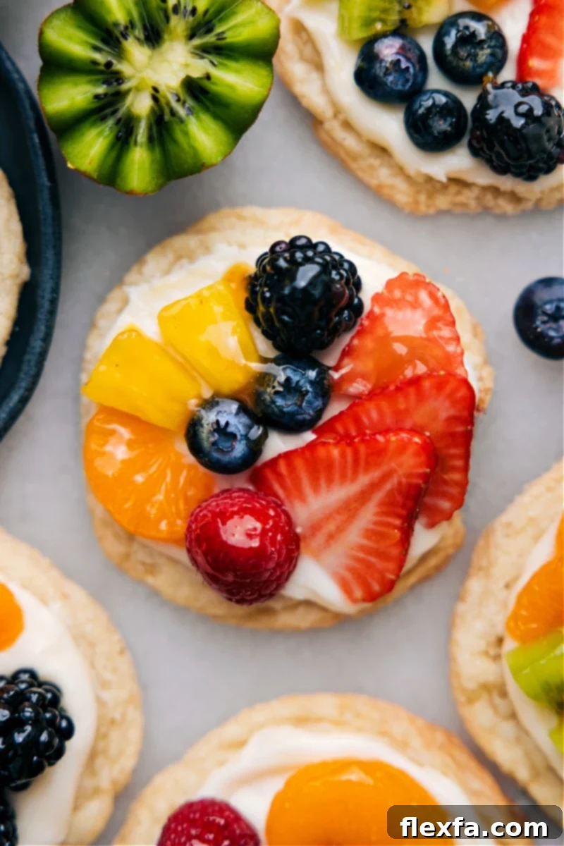 A high-angle, close-up view of a perfectly assembled Sugar Cookie Fruit Pizza, showcasing its vibrant fruit, creamy frosting, and glossy glaze, ready to be devoured.