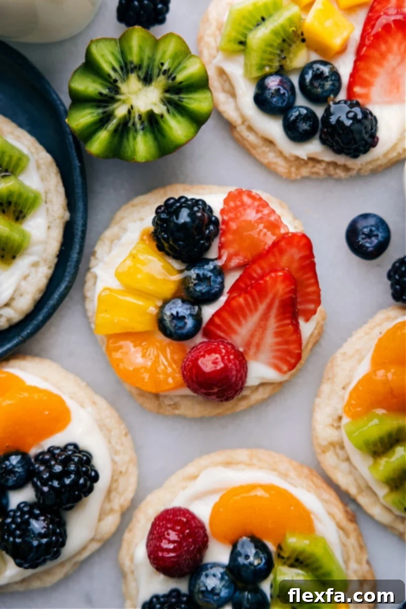An inviting overhead image showcasing multiple sugar cookie fruit pizzas artfully arranged on a platter, gleaming and ready to be served and savored.