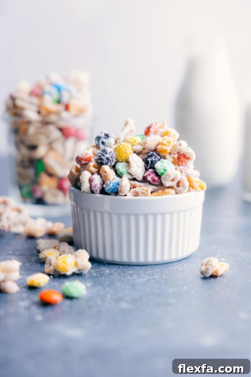 A vibrant bowl of White Chocolate Chex Mix, featuring cereal, pretzels, peanuts, and M&M's coated in white chocolate.