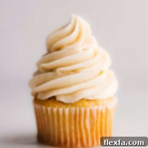 A delectable cupcake generously topped with perfectly piped vanilla frosting, adorned with colorful sprinkles.