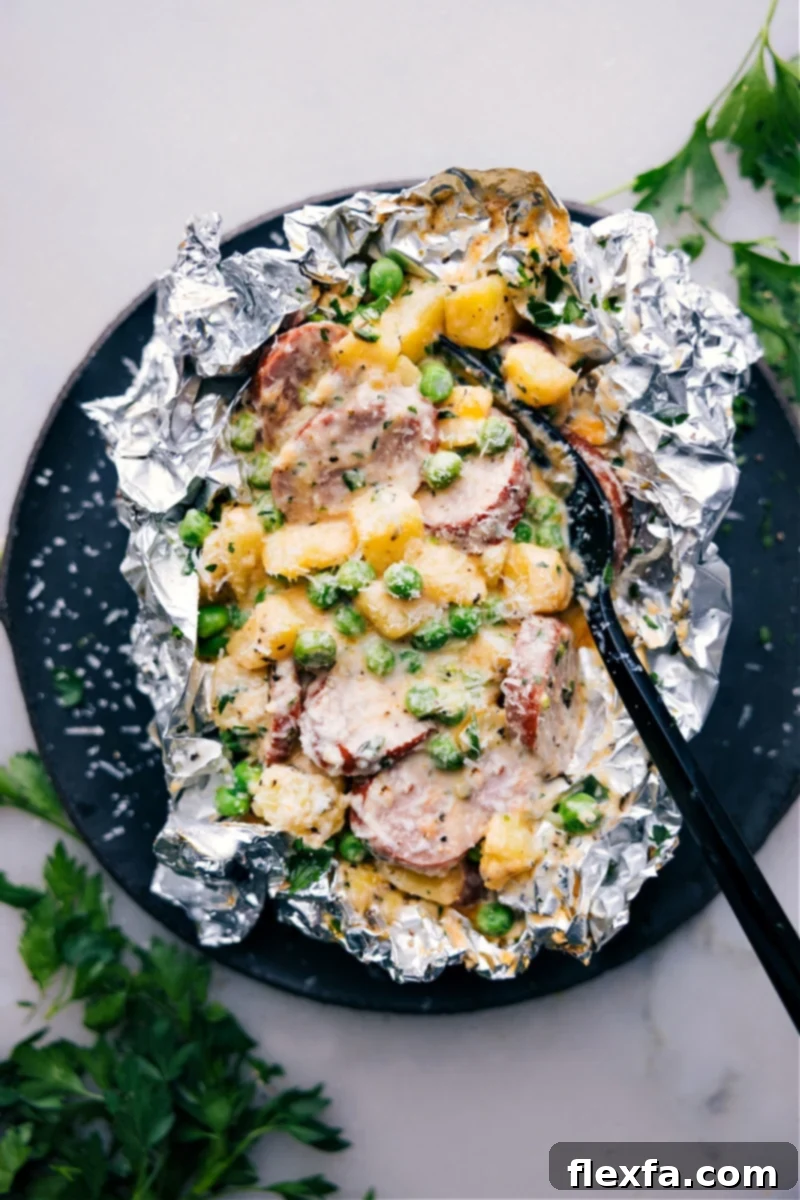 Overhead shot of Creamy Sausage and Potato Foil Packs, showcasing the savory smoked sausage, tender golden potatoes, and sweet peas smothered in a rich, creamy, cheesy sauce, ready to be enjoyed.