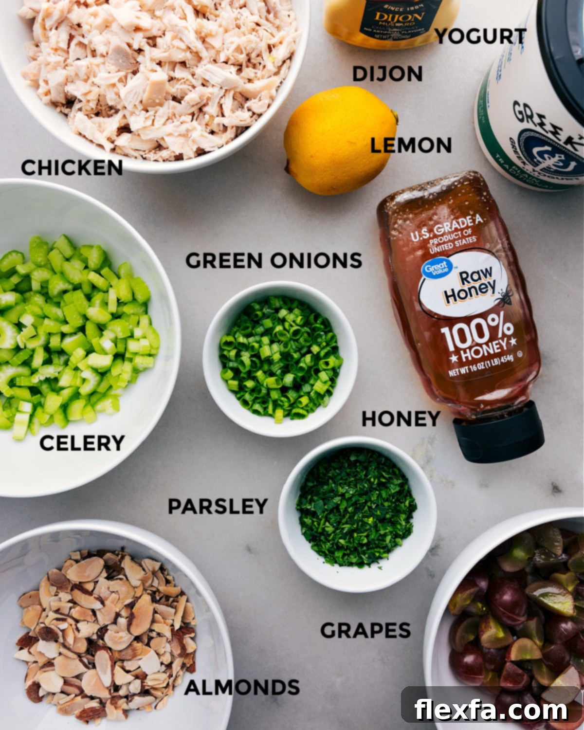 All the fresh ingredients for this healthy chicken salad recipe, including shredded chicken, celery, grapes, almonds, and herbs, prepped out for easy assembly.