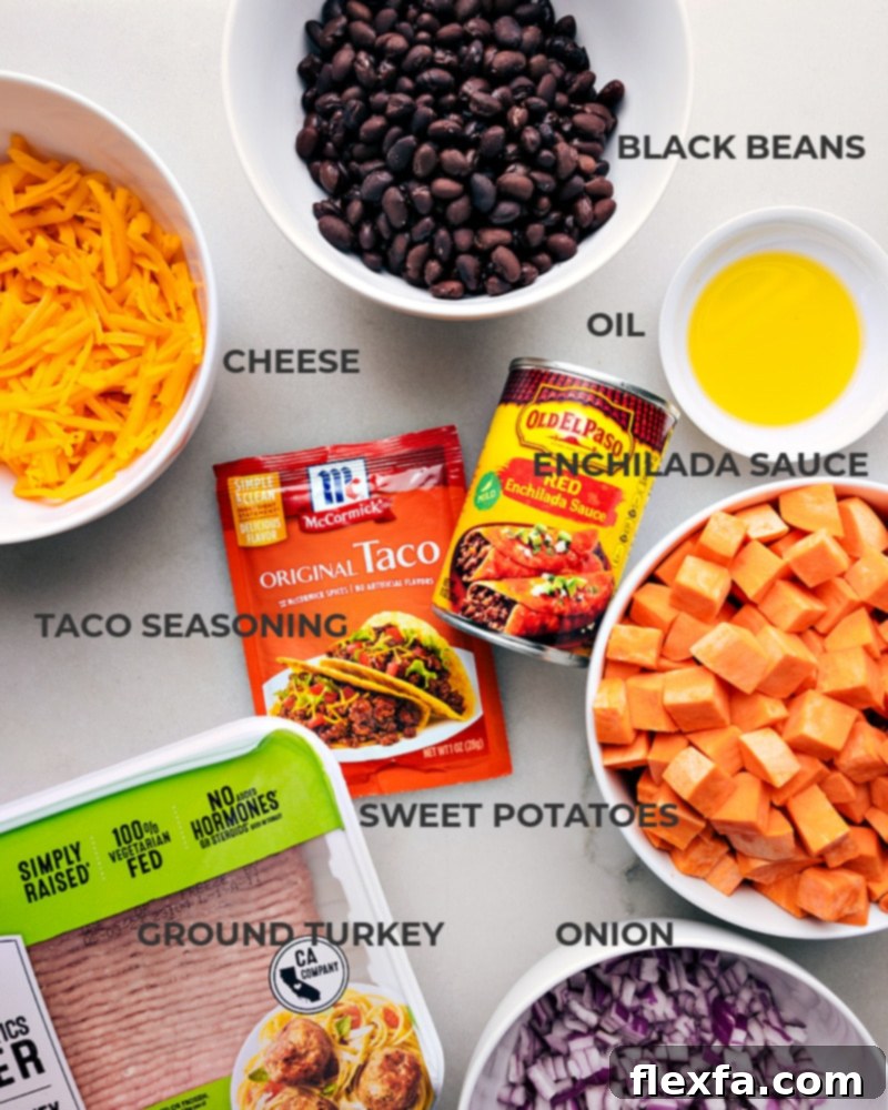All fresh ingredients neatly arranged for Sweet Potato Taco Foil Packets, including sweet potatoes, ground turkey, taco seasoning, onions, black beans, enchilada sauce, and cheddar cheese.