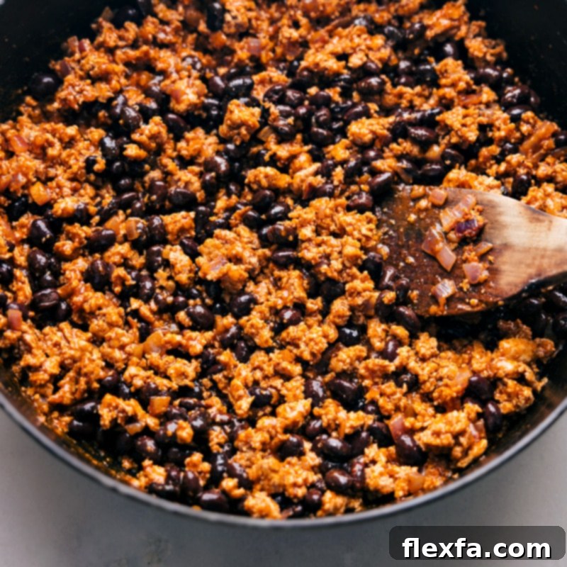 A pot filled with all the cooked ingredients for Sweet Potato Taco Foil Packets, including seasoned meat, sweet potatoes, and black beans, ready for assembly.