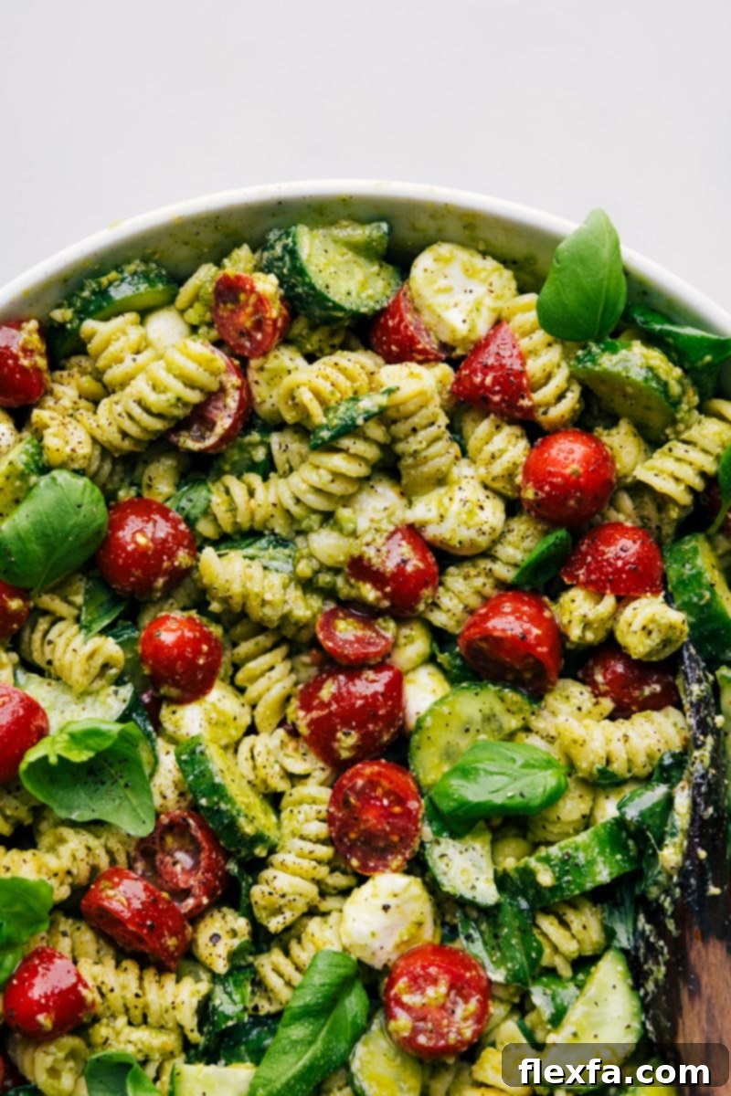 Fresh Pesto Pasta Delight 6 Up-close overhead image of the finished Pesto Pasta Salad, beautifully garnished with fresh basil, served in a large elegant white bowl, ready to be enjoyed.