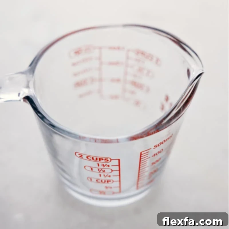 A clear liquid measuring cup on a kitchen counter, ready for precise measurement of fluids.