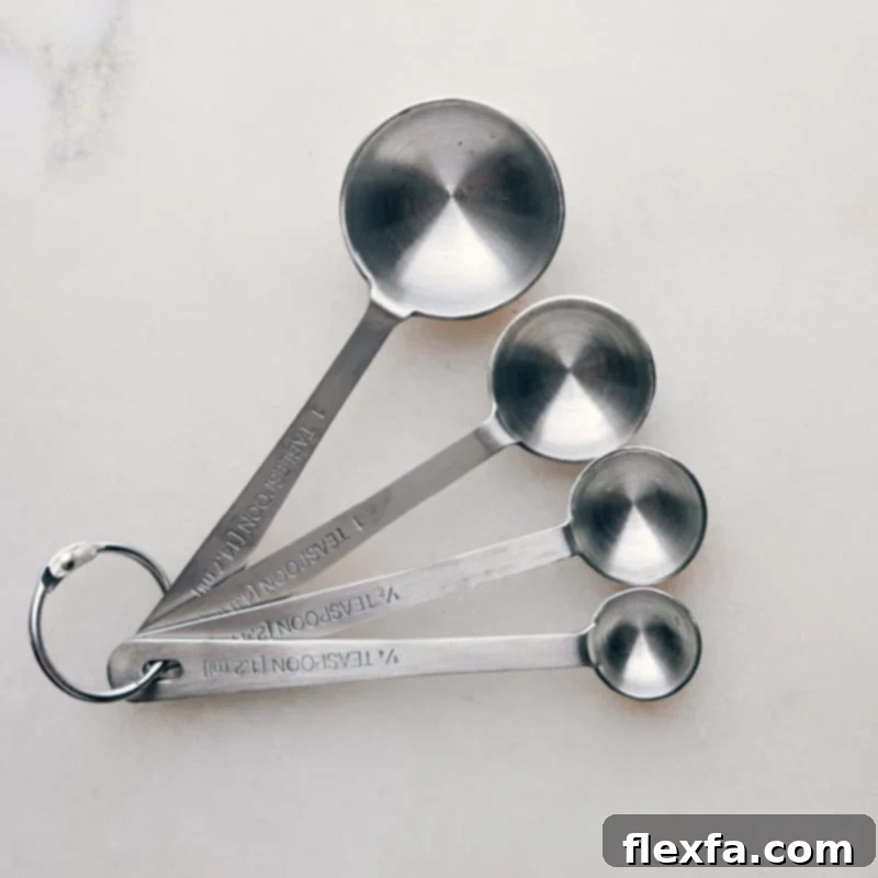 A set of metallic measuring spoons neatly arranged, signifying precision for small ingredient quantities.