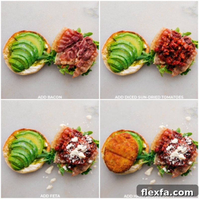 The final layers of the English Muffin Sandwich being assembled: crispy bacon, vibrant sun-dried tomatoes, crumbled feta, and a golden sweet potato hash brown patty being placed on top of the greens and avocado.
