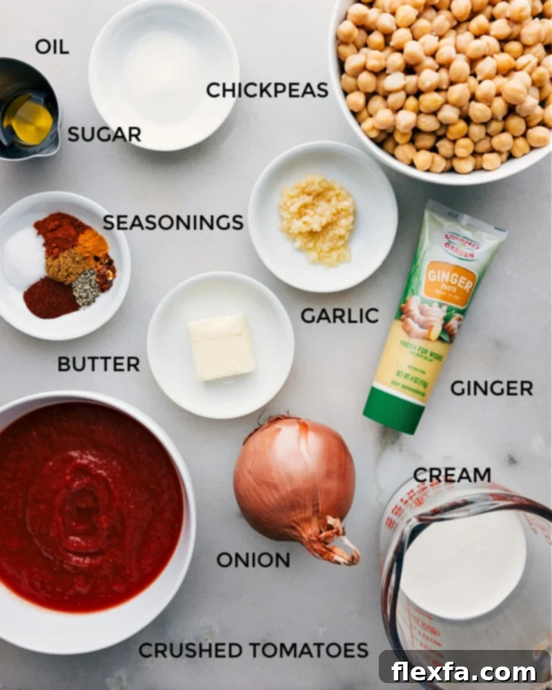 All the fresh ingredients for Butter Chickpeas laid out on a table, including onions, garlic, ginger, various spices, canned tomatoes, and chickpeas, ready for cooking.