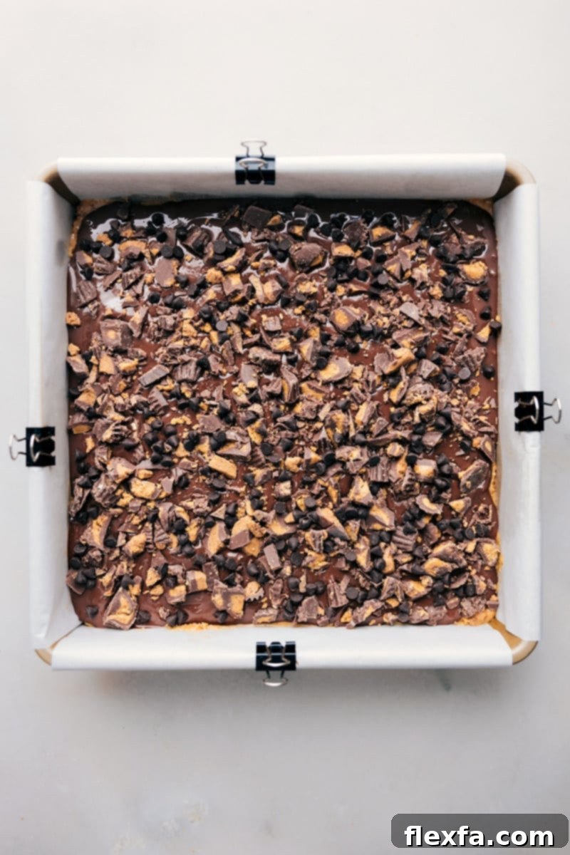 Overhead shot of freshly made Pretzel Peanut Butter Bars in the pan, garnished with toppings, ready to be sliced and enjoyed.
