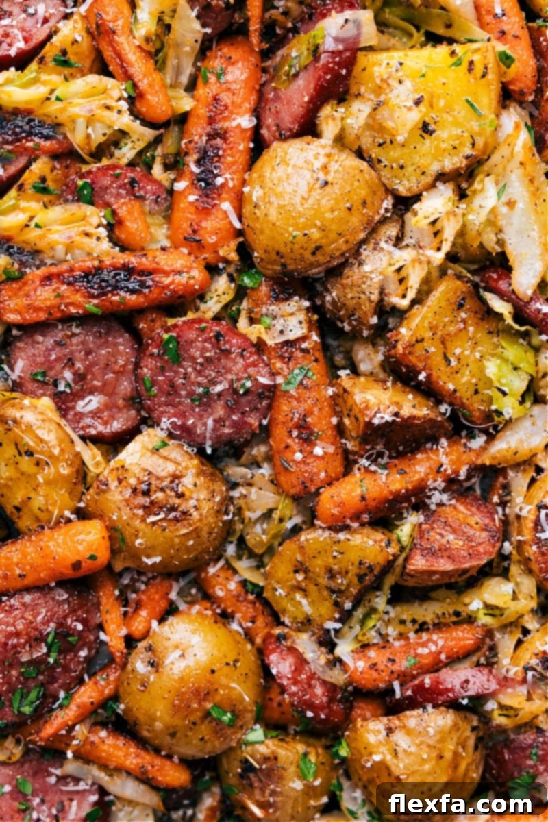 Our favorite Cabbage, Potatoes, and Sausage: a perfectly roasted one-pan meal, ready to enjoy with a creamy Dijon drizzle. Overhead image of the finished Cabbage, Potatoes, and Sausage dish, fresh out of the oven, garnished and ready to serve.