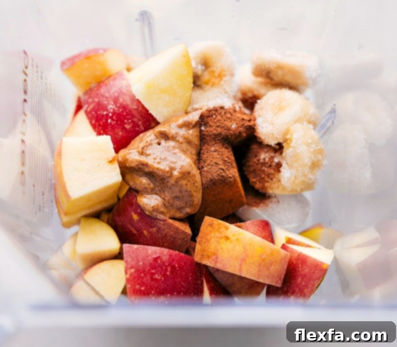 Fresh ingredients for Apple Pie Smoothie, including sliced apples, almond butter, banana, and spices, gathered around a blender, ready for preparation. Essential for a healthy breakfast or post-workout fuel.