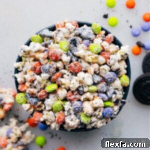 Close-up of a serving bowl filled with Halloween Popcorn, featuring white chocolate-coated popcorn, Halloween M&M's, and crushed Oreos.