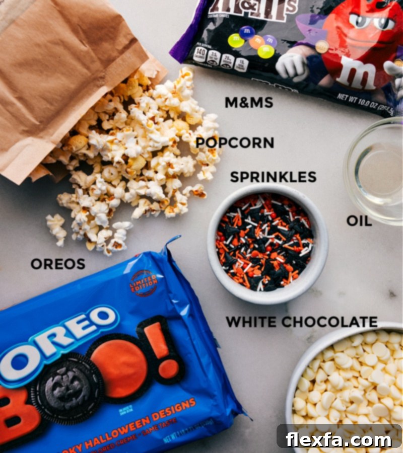 Ingredient shot: All the items needed for Halloween Popcorn, including popcorn, Halloween Oreos, M&Ms, white chocolate chips, and oil