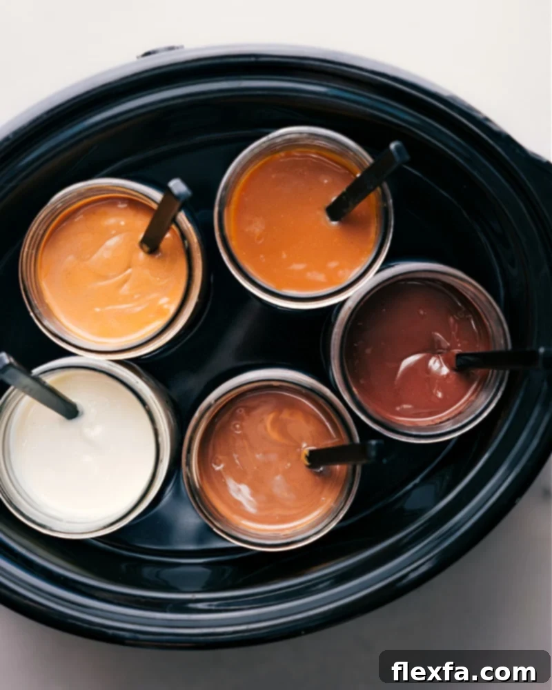 An overhead view of multiple warm dipping sauces, including caramel and chocolate, nestled in jars within a Crock-Pot, ready for a Caramel Apple Bar.
