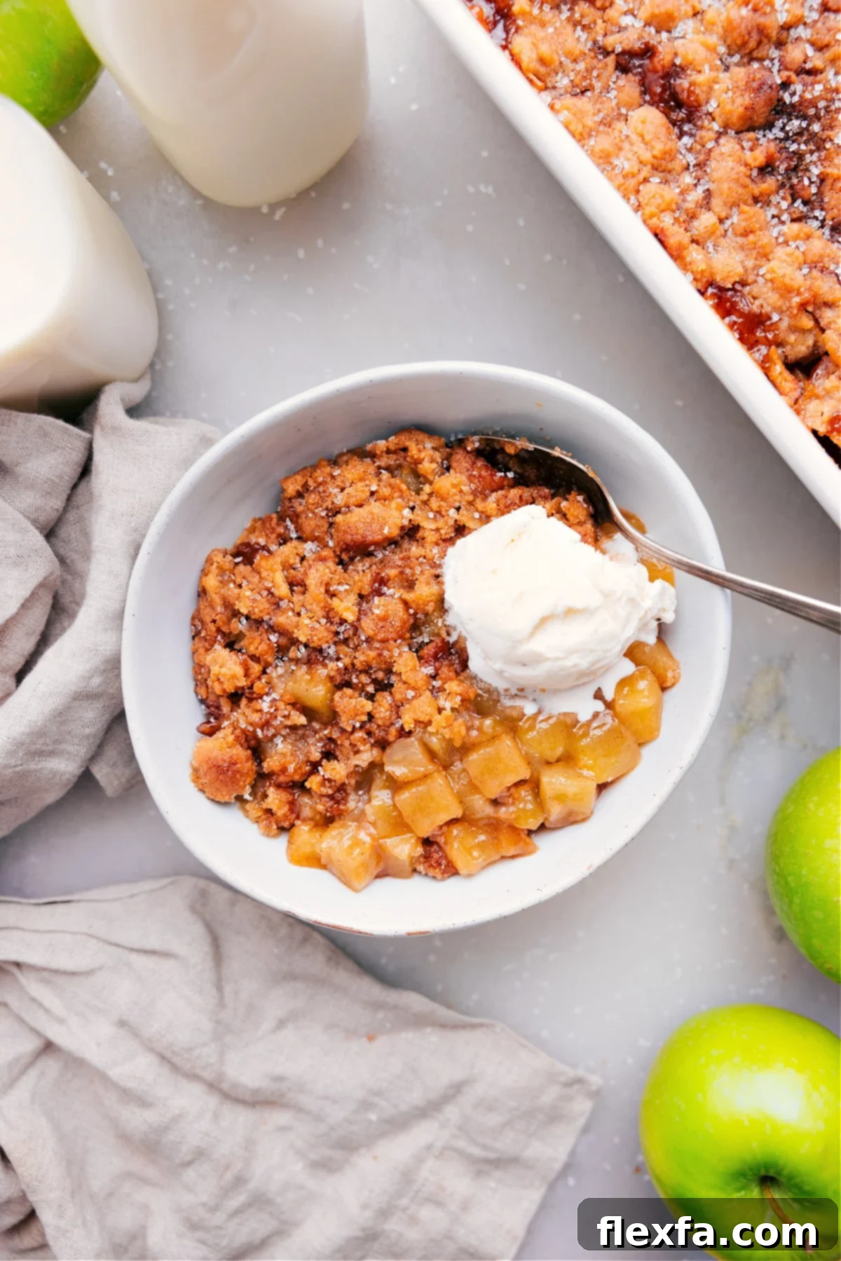 Apple cobbler recipe with a scoop of ice cream in a bowl with a spoon.
