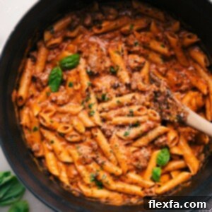 Penne Pasta with Italian Sausage in the Pot, garnished with fresh basil.