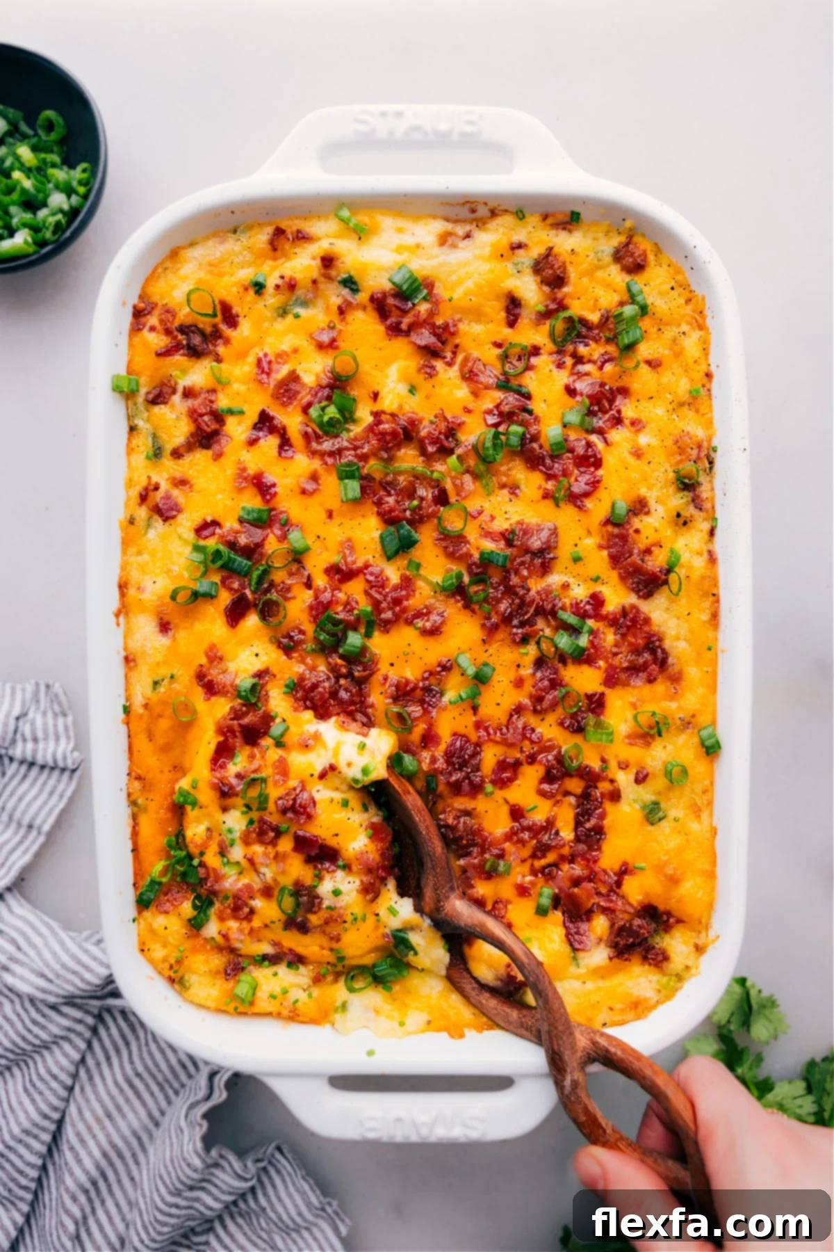 Twice-Baked Potato Casserole in a baking dish, garnished with fresh herbs.