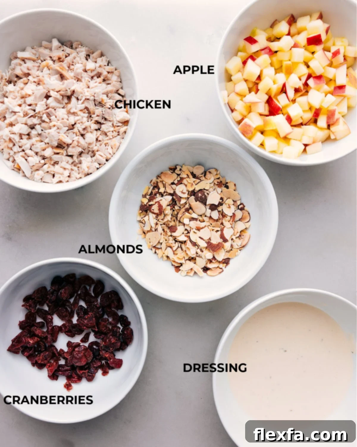 Assorted ingredients for a delicious chicken salad with apples displayed on a wooden board, ready for preparation.